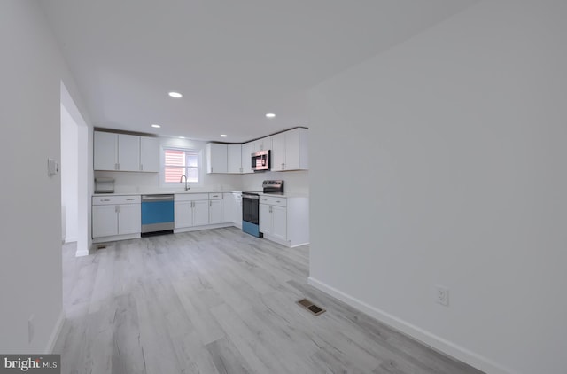 kitchen featuring appliances with stainless steel finishes, sink, light hardwood / wood-style flooring, and white cabinets