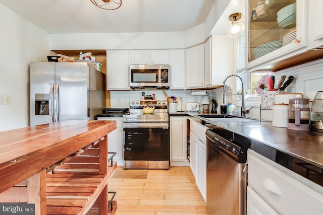 kitchen featuring light hardwood / wood-style flooring, backsplash, stainless steel appliances, sink, and white cabinets