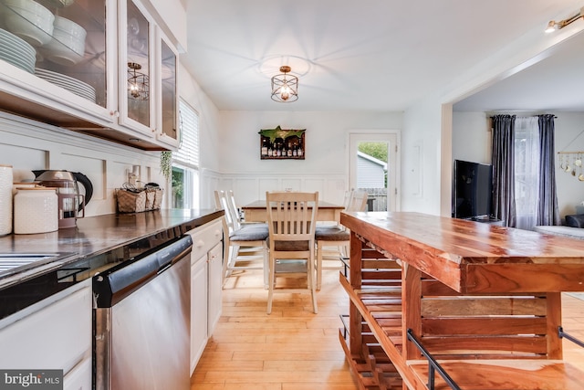 kitchen featuring butcher block countertops, white cabinets, light hardwood / wood-style floors, and stainless steel dishwasher