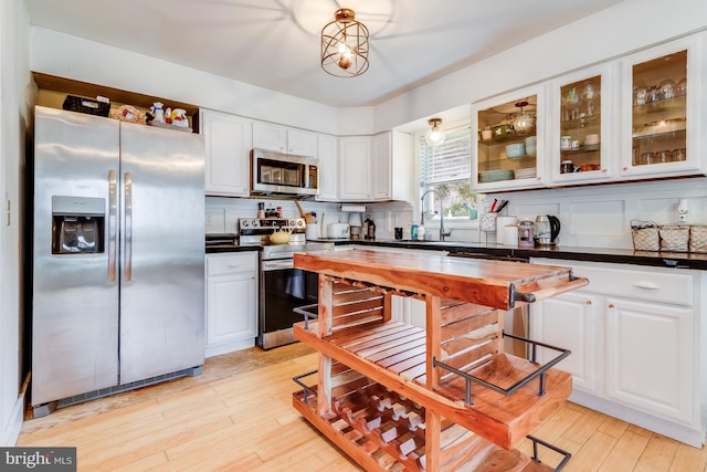 kitchen featuring light wood-type flooring, appliances with stainless steel finishes, white cabinetry, and sink