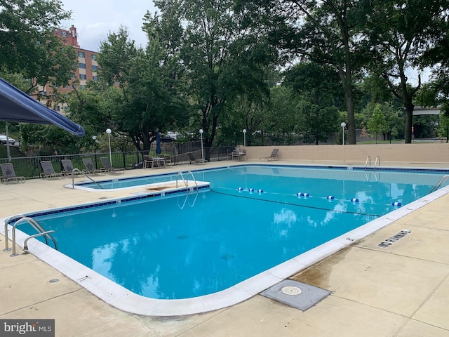 pool featuring fence and a patio