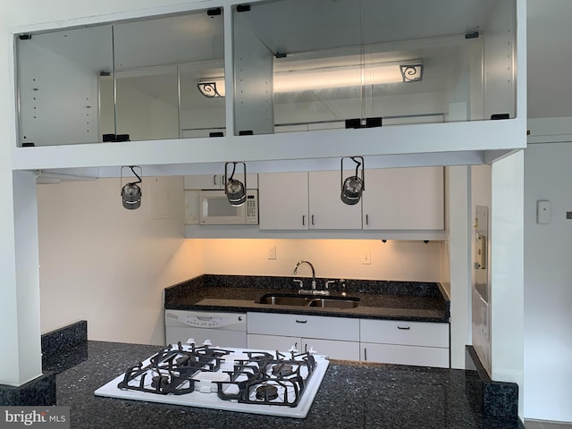 kitchen with white appliances, dark stone countertops, a sink, and white cabinets