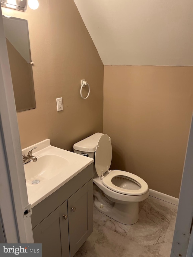 bathroom with toilet, lofted ceiling, and vanity