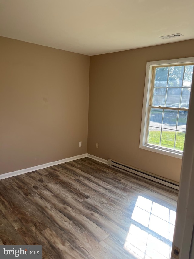 spare room with baseboard heating and wood-type flooring