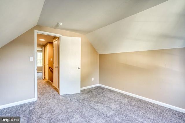 bonus room with light carpet and vaulted ceiling