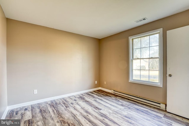 spare room featuring a baseboard heating unit and light hardwood / wood-style flooring