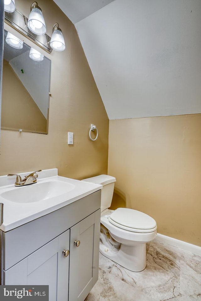 bathroom featuring toilet, vanity, and vaulted ceiling