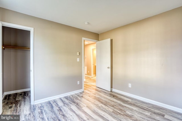 unfurnished bedroom featuring a closet, light hardwood / wood-style floors, and a walk in closet