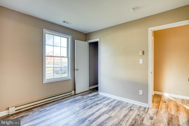 unfurnished bedroom featuring baseboard heating and light hardwood / wood-style flooring