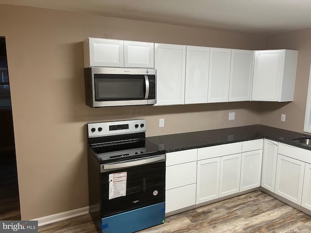 kitchen with black range with electric stovetop, white cabinetry, and light hardwood / wood-style flooring