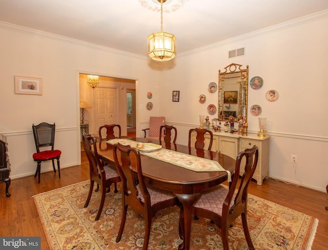 dining area with hardwood / wood-style flooring and crown molding