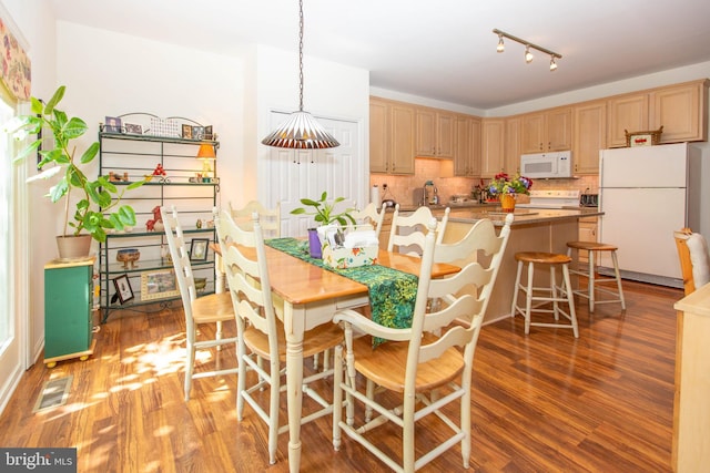 kitchen with hanging light fixtures, white appliances, backsplash, dark hardwood / wood-style floors, and light brown cabinetry