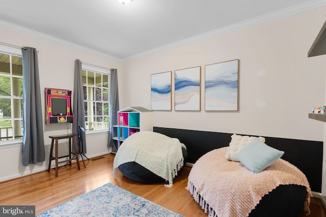 bedroom featuring ornamental molding, light wood-type flooring, and multiple windows