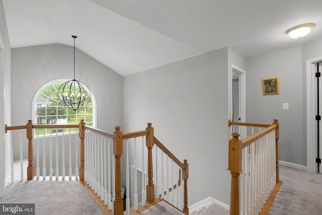 hall featuring lofted ceiling, carpet flooring, and an inviting chandelier