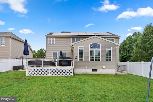 rear view of property with a lawn, solar panels, and a deck