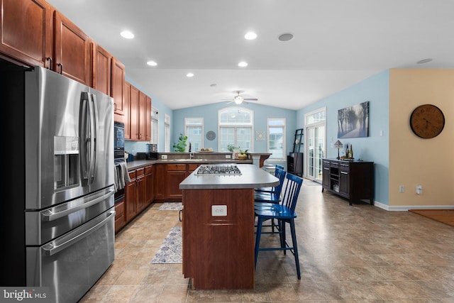 kitchen featuring stainless steel appliances, a kitchen breakfast bar, a kitchen island, ceiling fan, and lofted ceiling