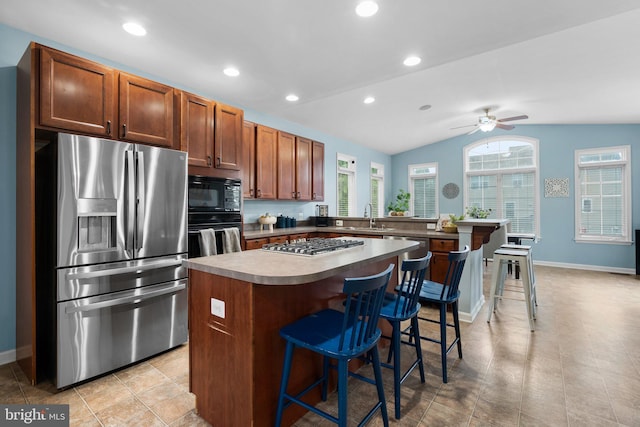 kitchen featuring a kitchen island, a kitchen breakfast bar, black appliances, lofted ceiling, and ceiling fan