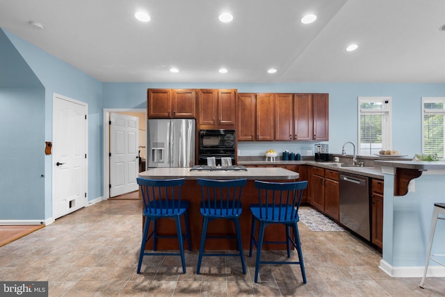 kitchen with stainless steel appliances, kitchen peninsula, sink, a kitchen island, and a breakfast bar area