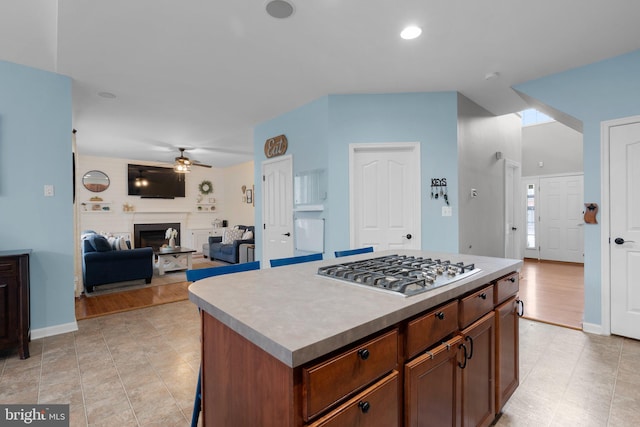 kitchen with a kitchen island, stainless steel gas cooktop, and ceiling fan