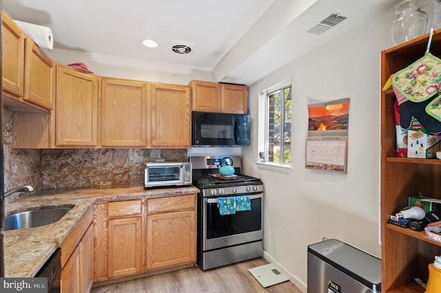 kitchen featuring black appliances, sink, backsplash, light stone counters, and light hardwood / wood-style flooring