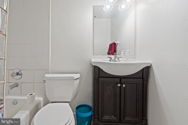 full bathroom featuring tiled shower / bath, vanity, and toilet