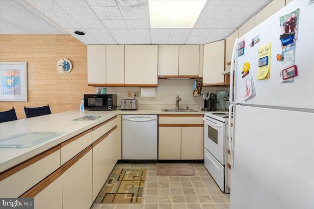 kitchen with wood walls, a paneled ceiling, sink, and white appliances