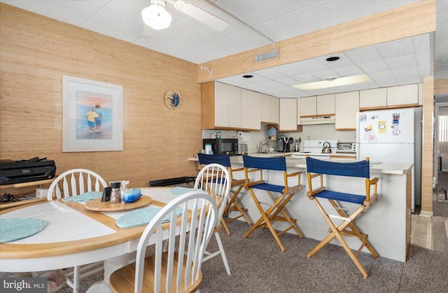 carpeted dining area featuring a paneled ceiling