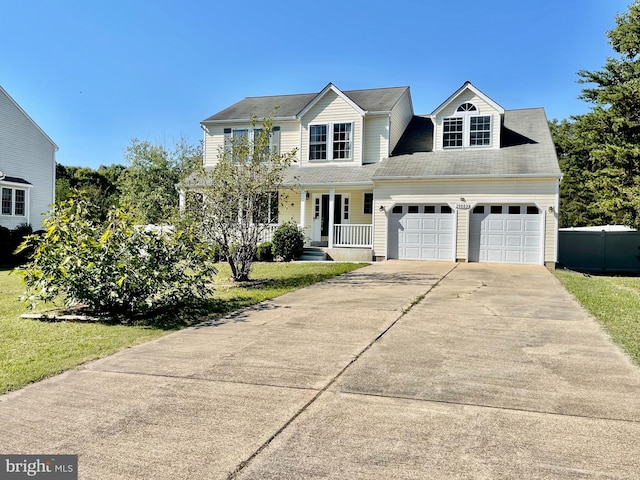 traditional-style house with fence, a porch, an attached garage, concrete driveway, and a front lawn