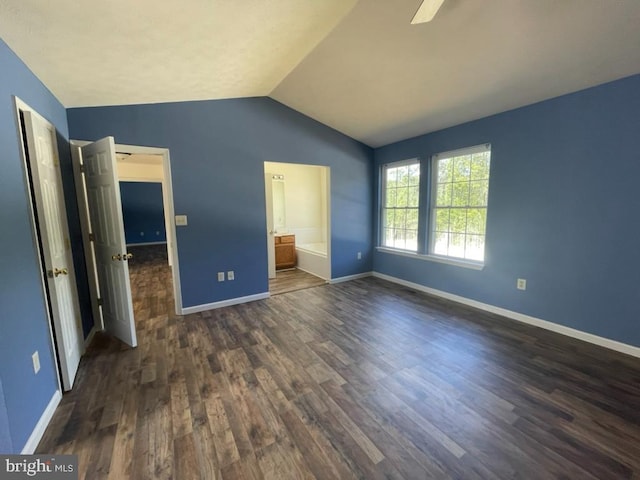 unfurnished bedroom with lofted ceiling, dark wood-type flooring, and connected bathroom