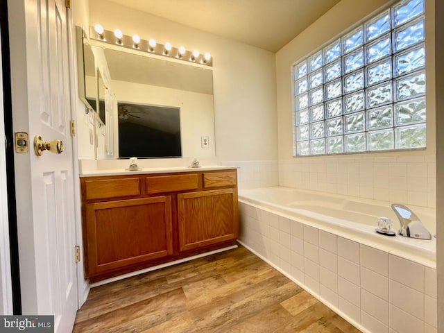 bathroom featuring hardwood / wood-style floors, vanity, and tiled bath