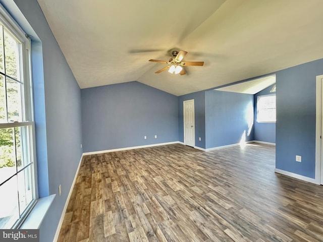 interior space with ceiling fan, baseboards, lofted ceiling, and wood finished floors