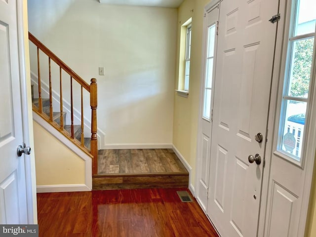 entrance foyer featuring visible vents, stairway, baseboards, and wood finished floors