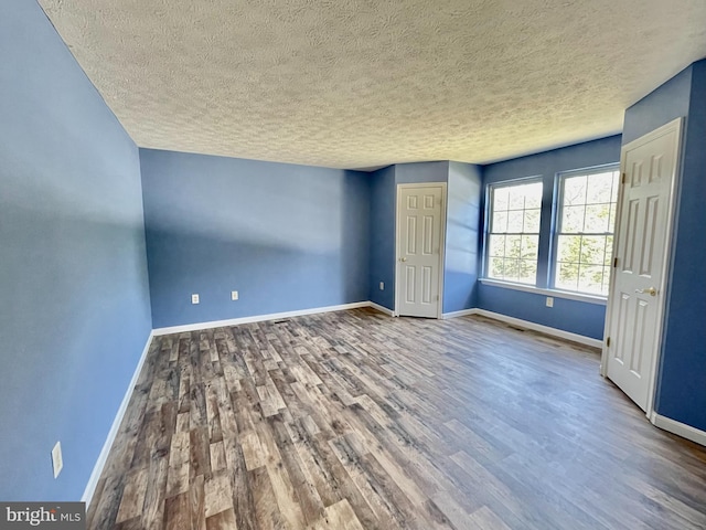 unfurnished bedroom with baseboards, a textured ceiling, and wood finished floors