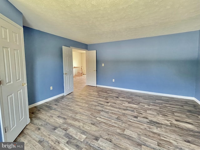 unfurnished bedroom with baseboards, a textured ceiling, and wood finished floors