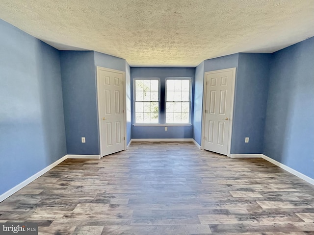 unfurnished bedroom featuring wood finished floors, baseboards, and a textured ceiling