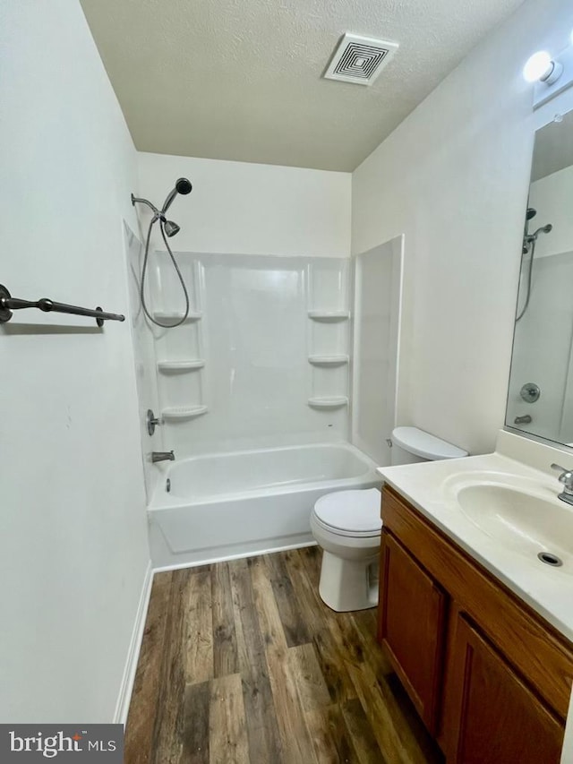 bathroom with vanity, wood finished floors, visible vents, a textured ceiling, and shower / bathing tub combination