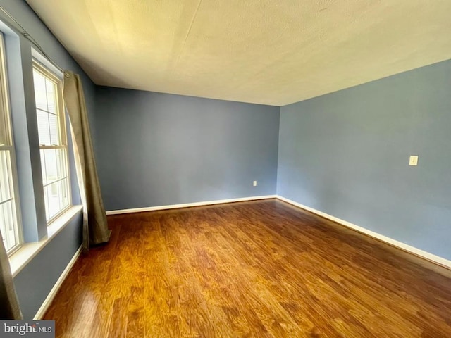 unfurnished room with baseboards and wood finished floors