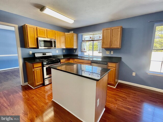 kitchen with dark wood-type flooring, sink, stainless steel dishwasher, and a textured ceiling