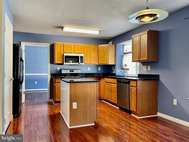 kitchen with baseboards, dark wood finished floors, appliances with stainless steel finishes, dark countertops, and a center island