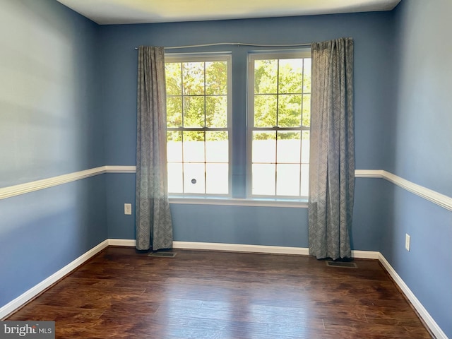 unfurnished room featuring dark wood finished floors, visible vents, and baseboards