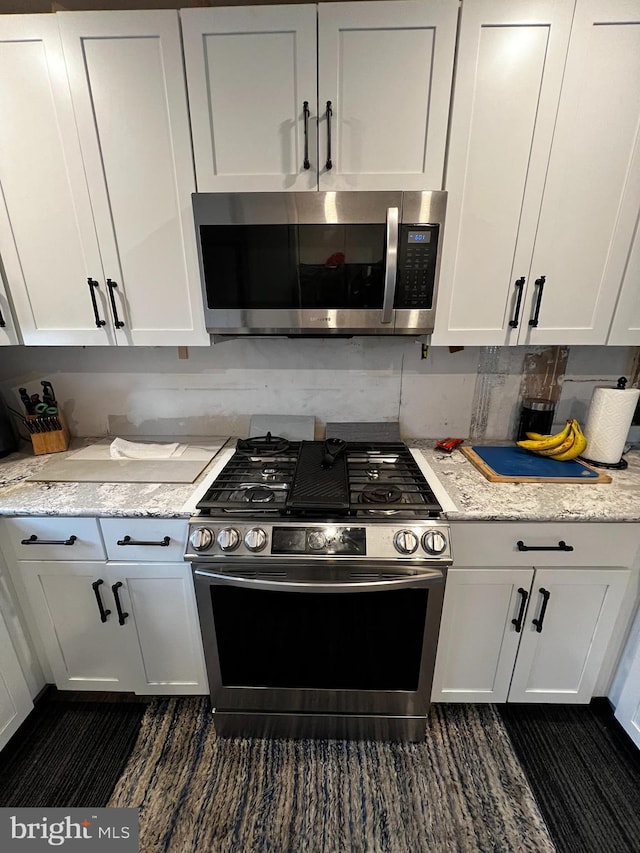 kitchen with appliances with stainless steel finishes, white cabinetry, and light stone countertops