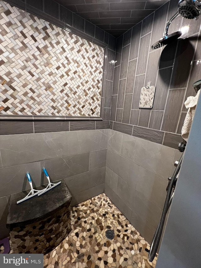 bathroom with tiled shower and tile walls