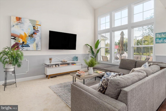 living area featuring high vaulted ceiling, carpet, and baseboards