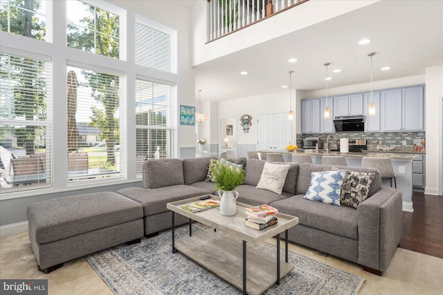 living area with a towering ceiling, light wood-style flooring, baseboards, and recessed lighting