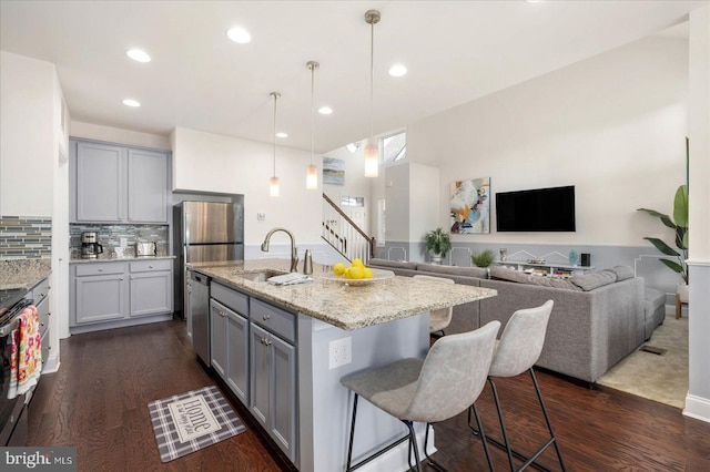 kitchen with a kitchen island with sink, pendant lighting, sink, and dark hardwood / wood-style floors