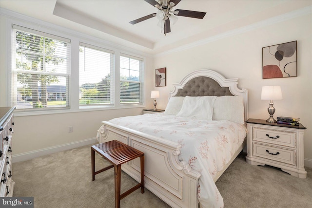 bedroom featuring ceiling fan, light colored carpet, a raised ceiling, and crown molding