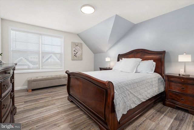 bedroom featuring vaulted ceiling, baseboards, and wood finished floors