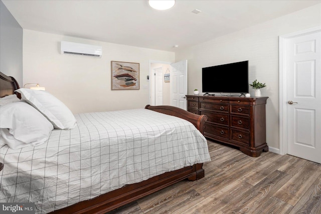 bedroom featuring a wall mounted AC and light hardwood / wood-style floors