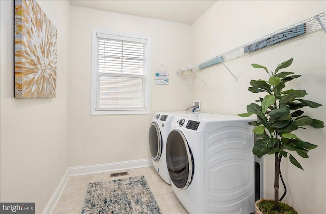 clothes washing area featuring light tile patterned floors, laundry area, visible vents, baseboards, and washer and clothes dryer