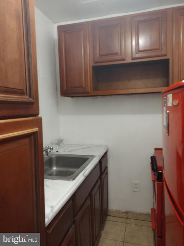 kitchen with refrigerator, light tile patterned floors, and sink